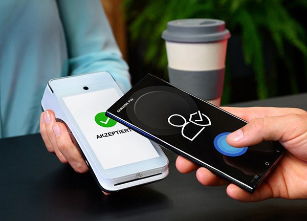 Ein Smartphone wird an ein Kartenleseger&auml;t f&uuml;r einen kontaktlosen Bezahlvorgang gehalten.