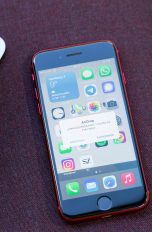 iPhone AirDrop Ein iPhone SE liegt neben einem MacBook. Auf dem Display des Smartphones ist eine AirDrop-Meldung zu sehen.