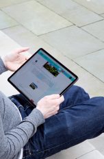 Eine Person sitzt auf einer Treppenstufe und hält ein iPad Pro in der Hand. Eine Person sitzt auf einer Treppenstufe und hält ein iPad Pro in der Hand.