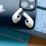 Zwei AirPods liegen auf der R&uuml;ckseite eines iPhones.