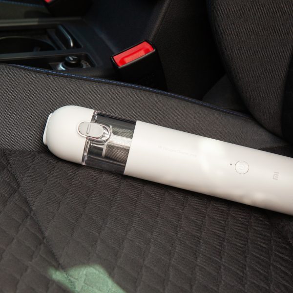 Der Xiaomi Mi Vacuum Cleaner Mini liegt auf einem Autositz mit Stoff-Bezug.
