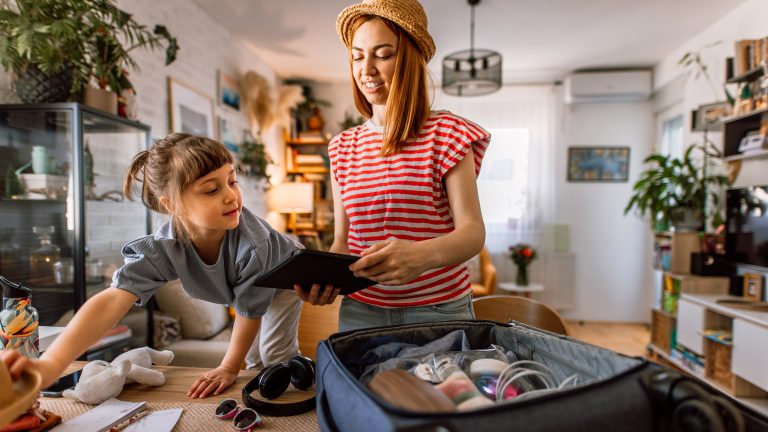 Zwei Personen packen Kleidung in einen Koffer und bereiten Reiseutensilien vor.